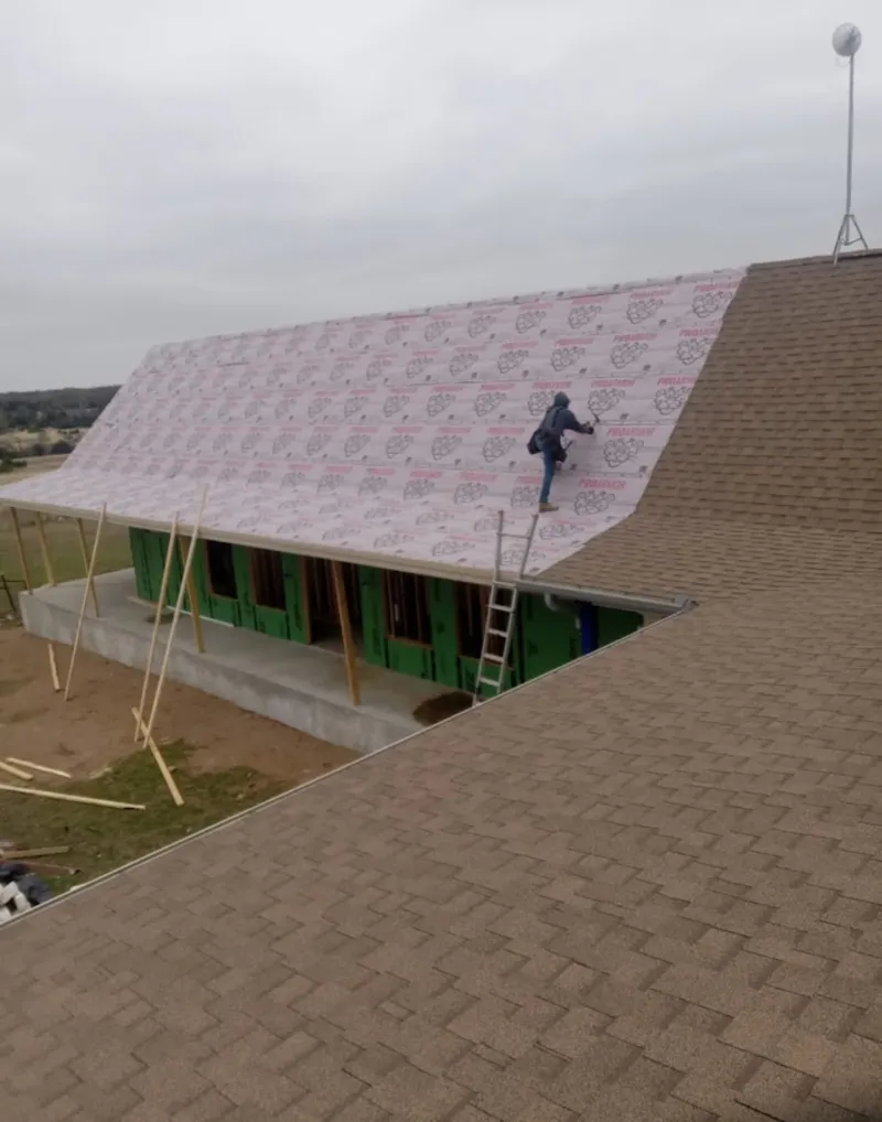 Worker preparing underlayment for a metal roof installation in Topanga
